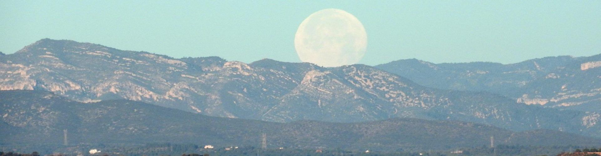 Una gran lluna, amagant-se entre les muntanyes